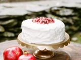 a white buttercream wedding cake topped with pomegranate seeds, with pomegranates around is a lovely idea for a fall or winter wedding