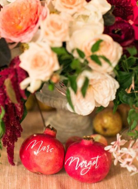 substitute usual wedding seating cards with pomegranates and paint names using gold calligraphy on them