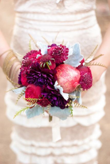a bold and playful wedding bouquet of pale greenery, deep red and burgundy blooms and pomegranates is a fantastic idea for the fall