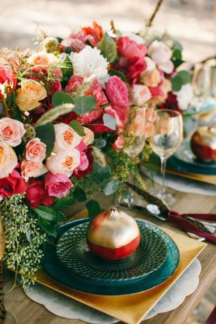 a bright wedding tablescape with super bold blooms, gold chargers, green plates and a gilded color block pomegranate for an accent