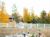 a simple and relaxed backyard wedding tablescape with an uncovered table, lace runner and neutral napkins, pastel florals and greenery and candles wrapped with leaves is a cool idea for a laid-back wedding