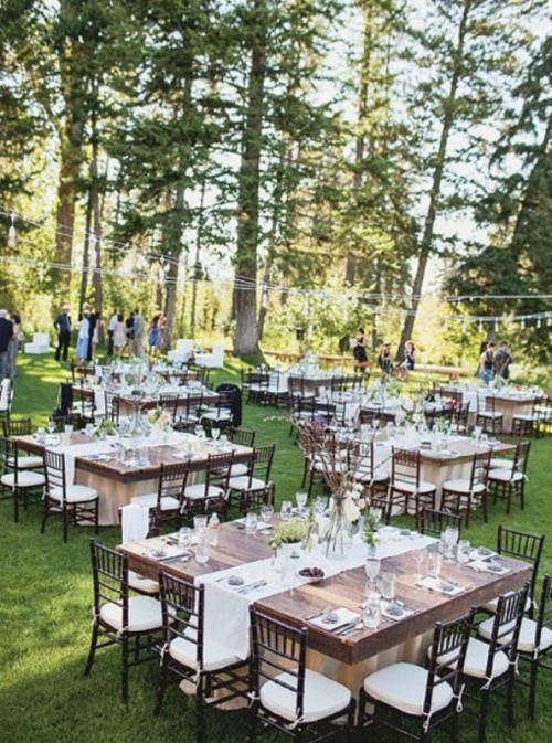 a lovely backyard wedding reception with neutral linens, with branch centerpieces, candles and elegant chairs is cool