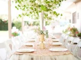a glam backyard wedding tablescape with a tulle and sequin tablecloth, greenery and neutral blooms, pink glasses and gold cutlery is beautiful and easy to make