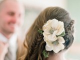 a creative wedding half updo with braids and waves and some blooms to accent the hairstyle looks awesome