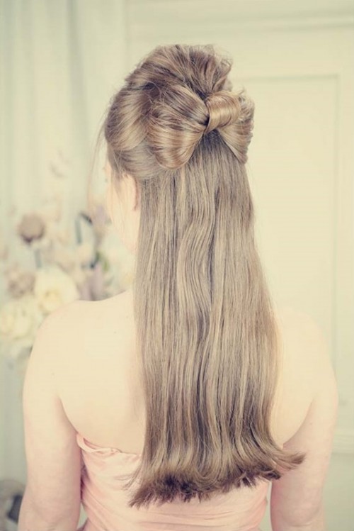 a creative retro-inspired half updo with a volume on top and a bow of hair and long hair down is a cool and chic idea