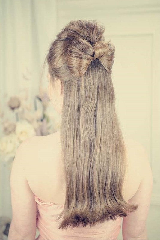 a creative retro inspired half updo with a volume on top and a bow of hair and long hair down is a cool and chic idea