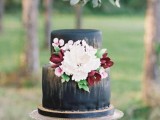 a matte black wedding cake with gold touches and fresh and sugar blooms and leaves is a beautiful idea for a fall wedding