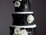 a white wedding cake with black covers, white sugar blooms and pearls is a stylush and catchy idea for a vintage-inspired wedding