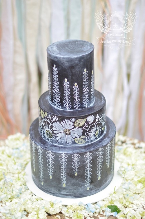 a black chalkboard wedding cake with patterns and blooms that seem to be drawn with chalk looks fantastic, chic and gorgeous