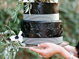 a textural black wedding cake with striped ribbons and white anemones and greenery is a stylish idea for a moody wedding