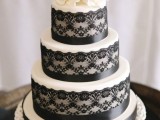a white wedding cake with black lace and black ribbon, with white blooms and black twigs on top is a classic idea for a vintage wedding in a monochromatic color scheme