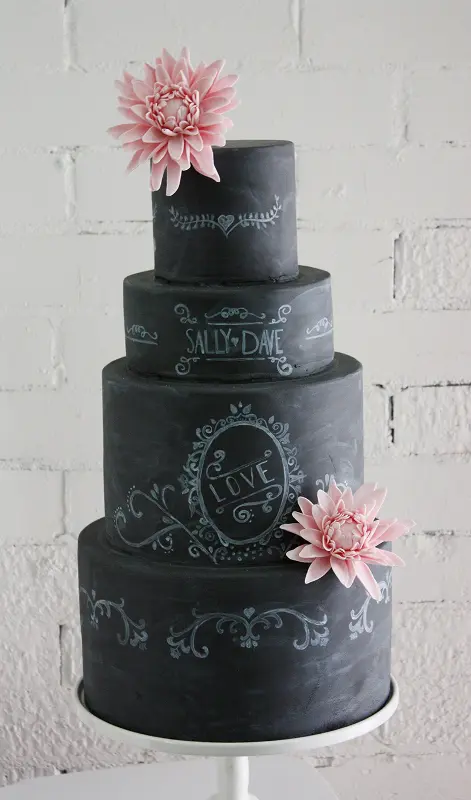 a black chalkboard wedding cake with chalk patterns and images and fresh pink blooms for a contrasting and eye-catchy look