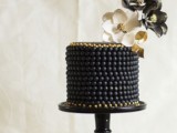 an elegant black bead covered wedding cake with black, gold and white sugar blooms on top is a gorgeous idea for a modern and exquisite wedding