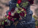 a textural black wedding cake with burgundy and red blooms, greenery, feathers and succulents is a unique idea to try