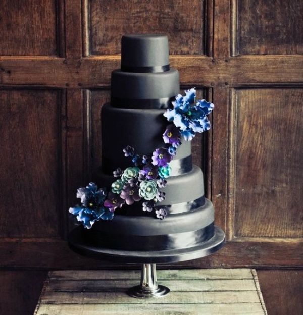 A sleek and plain wedding cake with black ribbons, with blue, green and purple sugar blooms is a stylish idea for a moody wedding with a touch of color