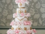 a white wedding cake with gold decor and pink sugar blooms is a chic glam idea for a vintage wedding