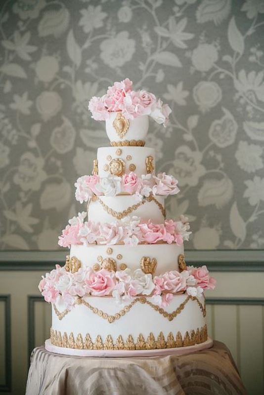A white wedding cake with gold decor and pink sugar blooms is a chic glam idea for a vintage wedding