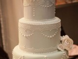 a pastel green wedding cake decorated with white lace touches, white sugar blooms and beads is a chic idea