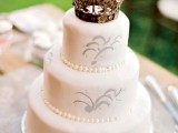 a white wedding cake with patterns and a pretty crown topper is really a royal idea
