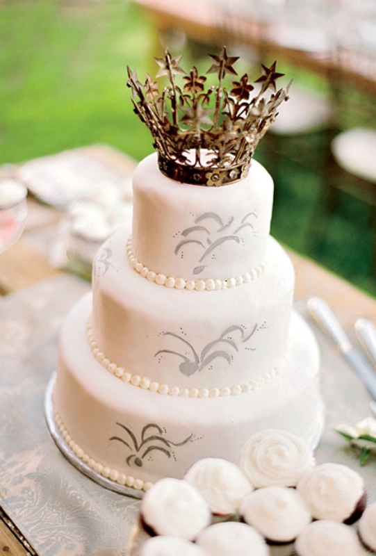 A white wedding cake with patterns and a pretty crown topper is really a royal idea