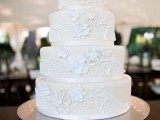 an ivory wedding cake with white lace decor and sugar blooms on top is vintage-style classics
