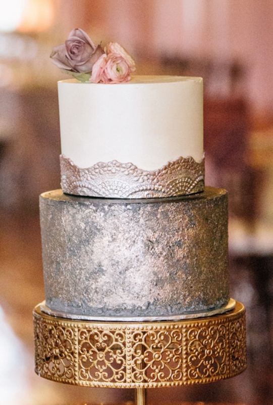 A refined wedding cake witha  copper tier and a white and copper tier plus mauve and pink blooms on top