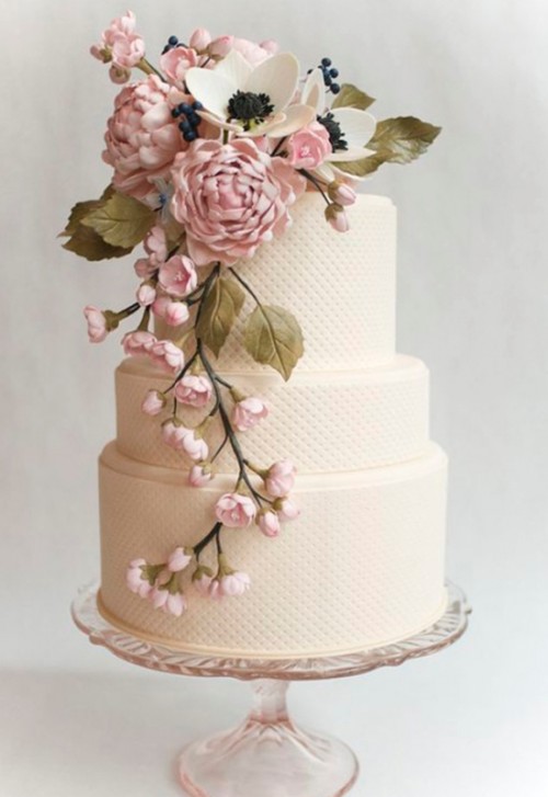 a neutral textural wedding cake with pink and white sugar blooms and greenery cascading