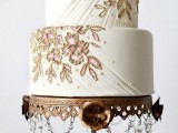 a white textural wedding cake with beading and gold and pink floral detailing is a sophisticated idea