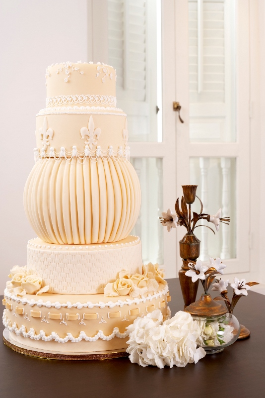 A creative neutral wedding cake with multiple tiers, lace decor and sugar blooms is a whimsy idea for a vintage wedding