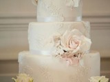 a white lace wedding cake with silk ribbons, white and blush natural blooms for a refined feel