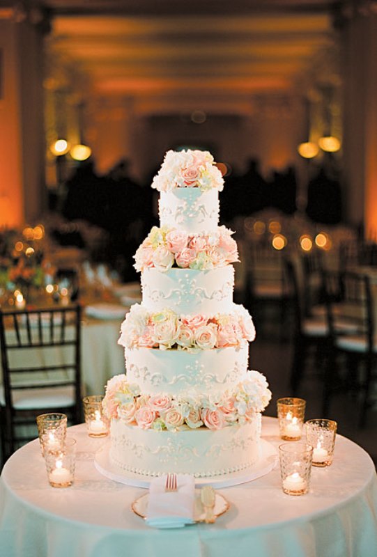 A white wedding cake with beautiful patterns and blush roses is a stylish and elegant idea