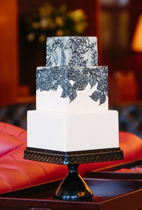 A black and white wedding cake with black lace decor is vintage inspired, yet chic and refined