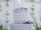 a lilac wedding cake with white lace and purple and lilac blooms and greenery is a whimsy and chic idea