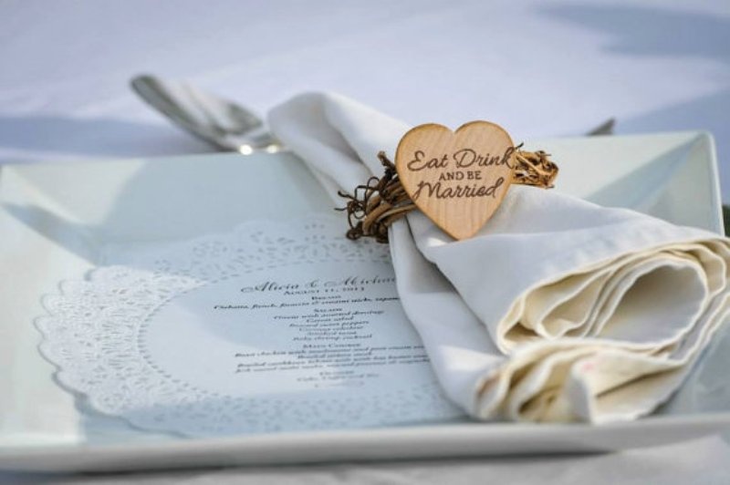 an elegant neutral place setting with a square plate, a doily menu and a neutral napkin with a wooden tag with calligraphy is a chic idea for a rustic wedding