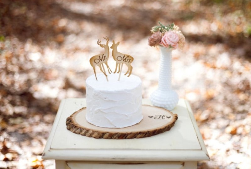 a wood slice as a plate for a simple white wedding cake with wooden deer toppers is a lovely idea for a woodland wedding