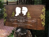 a large dark-stained wooden sign with calligraphy and silhouettes is a cool idea for a modern wedding with a cozy woodland feel
