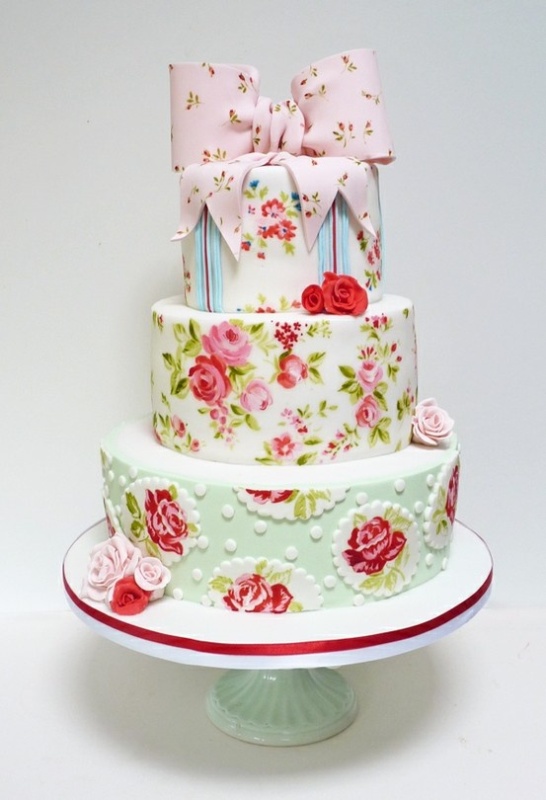a creative floral wedding cake with all mismatching painted tiers, and with a sugar floral pink bow on top is a lovely idea