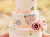 a white wedding cake decorated with pink ribbons and pastel painted florals plus fresh blooms is a beautiful idea for a spring or summer wedding
