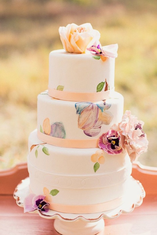 a white wedding cake decorated with pink ribbons and pastel painted florals plus fresh blooms is a beautiful idea for a spring or summer wedding