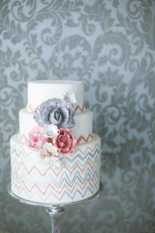 a white buttercream wedding cake with painted grey and coral patterns and matching sugar blooms is a cool idea for a summer or fall wedding