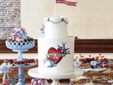 a white buttercream handpainted wedding cake with a colorful heart and birds and a flag cake topper is amazing for a bright wedding