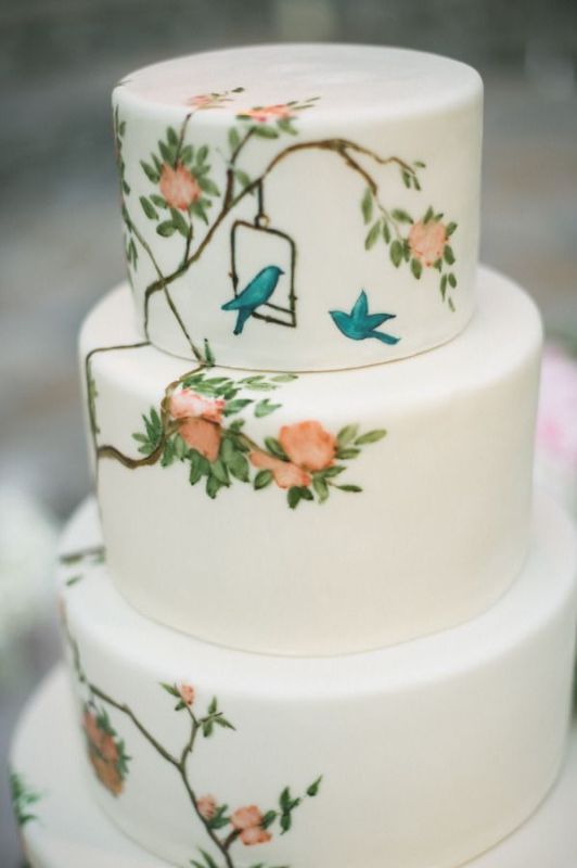 a white buttercream wedding cake with handpainted blooms and birds is a lovely idea for a spring or summer wedding, it looks very pretty and whimsy