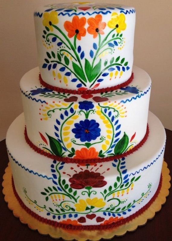 a white buttercream wedding cake with painted bright blooms and leaves done in boho and folk style, ideal for a Mexican wedding