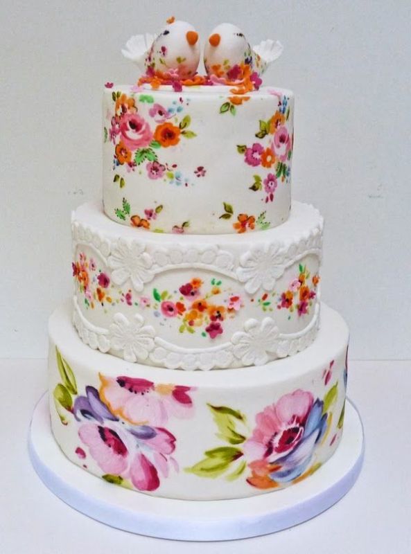 a white wedding cake decorated with bright handpainted blooms and leaves, with painted little bird cake toppers is an amazing idea for a bright wedding