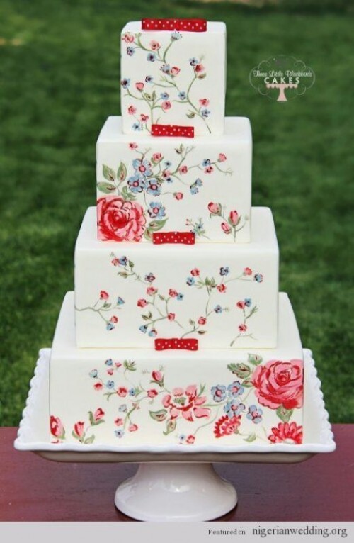 a square white wedding cake with bright painted flowers and a bit of greenery plus tiny red ribbon bows is a bold idea for a summer wedding