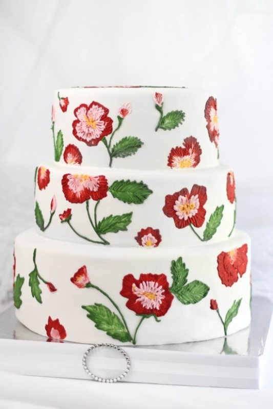 a white buttercream wedding cake with painted blooms and leaves that look like embroidered ones is a unique idea for a relaxed wedding