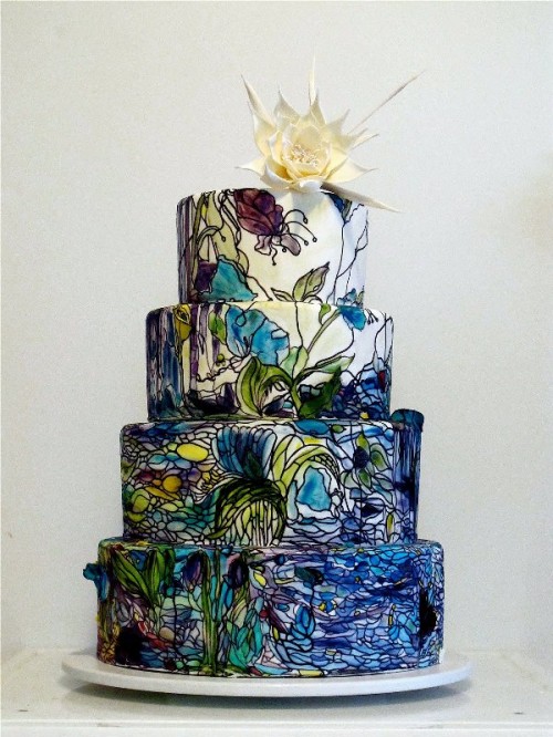 a dark-colored wedding cake with green and navy painted blooms in Monet style and a white sugar bloom on top is amazing