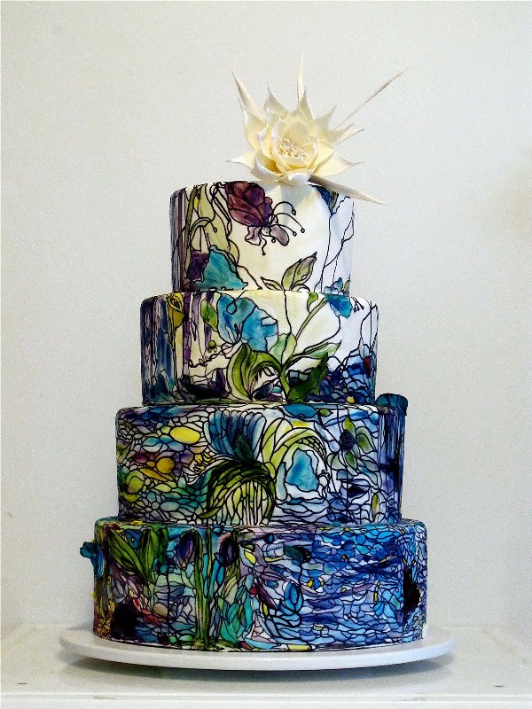 a dark colored wedding cake with green and navy painted blooms in Monet style and a white sugar bloom on top is amazing