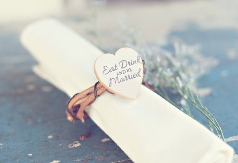 a vine napkin ring with a plywood heart with wood burning is a pretty and cool idea for a rustic or just relaxed wedding