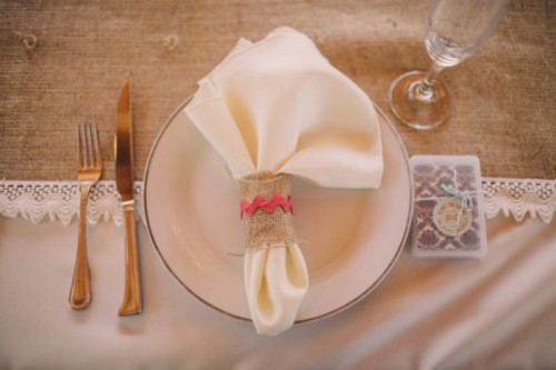 a bright coral string and burlap napkin ring is a chic and cool accent to a rustic wedding tablescape